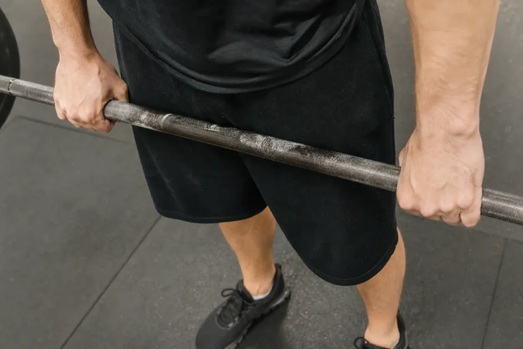 Närbild på händer som håller ett skivstångshandtag på gymmet under ett träningspass på semestern.