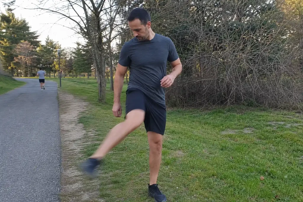 Man gör benswingar som uppvärmning i en park, del av ett träningsprogram hemma