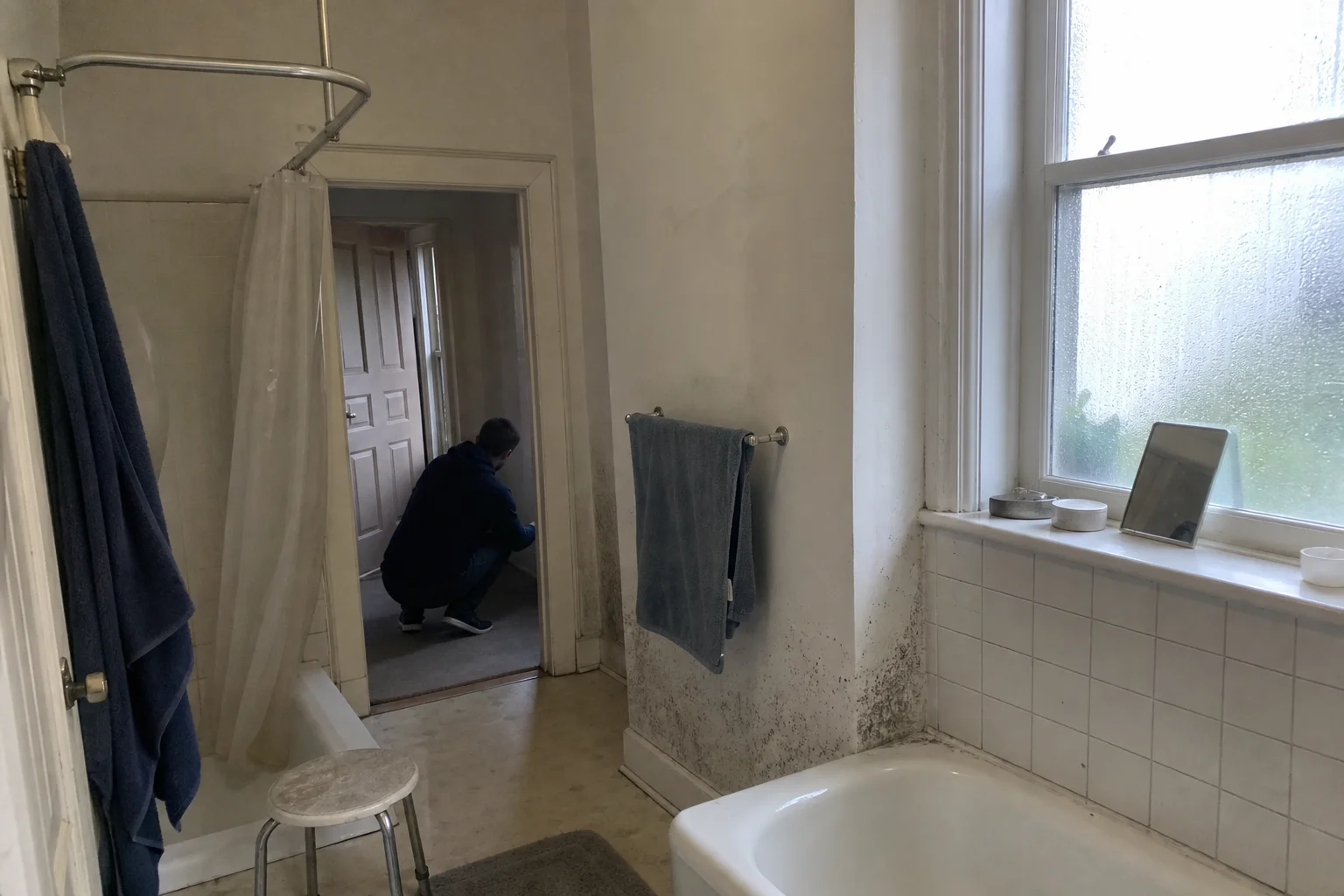 Fuktskadat badrumshörn med mörka fläckar i fogen, ett exempel på mögel i hemmet symptom du bör känna till.