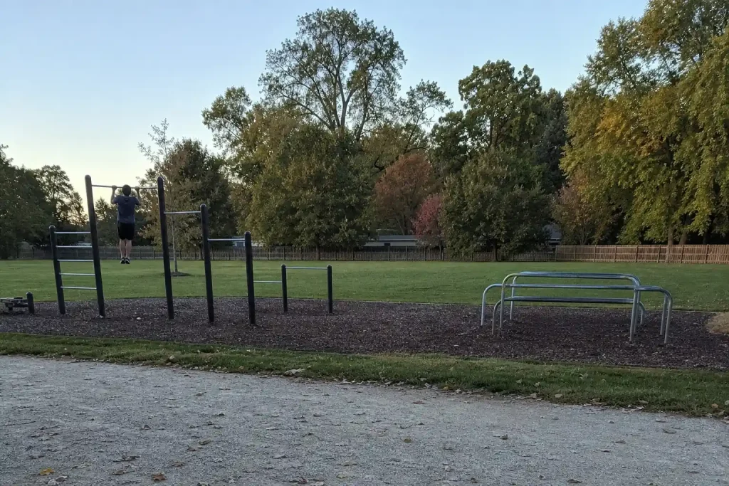 Utomhusgym i parken där en person hänger i pullup-räcket, ett exempel på att träna som en apa, bli stark som en gorilla.