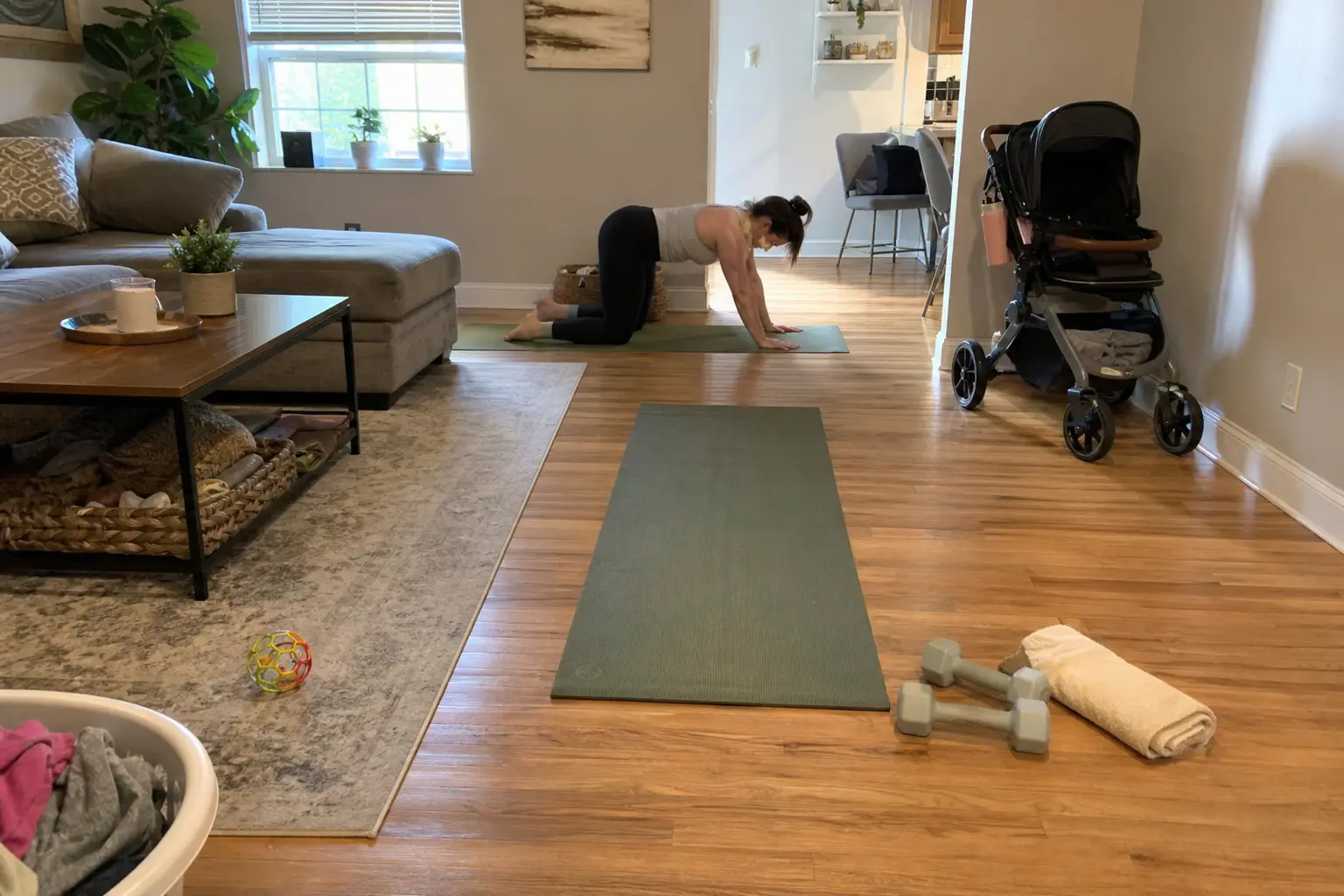 TV: Nyförlöst? Så tränar du upp mammakroppen: kvinna gör golvövning på yogamatta i ljust vardagsrum med barnvagn i bakgrunden