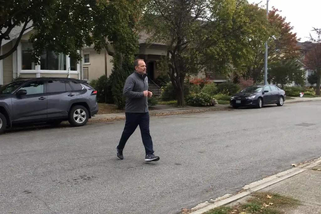 Medelålders man joggar på villagata en overcast förmiddag, en vardaglig aktivitet som kan stödjas av omega-3.
