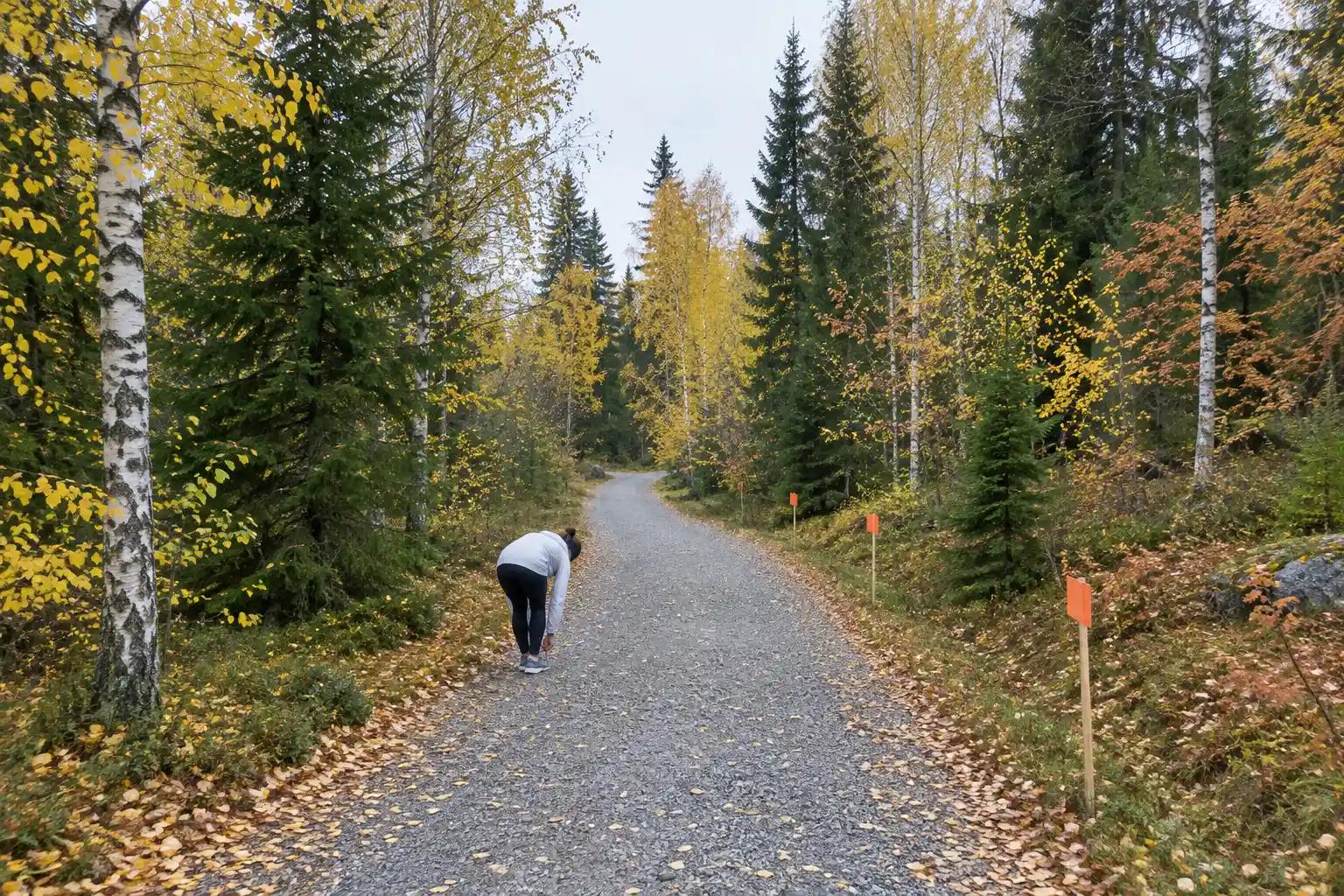 Löpare knyter skon på en grusstig i höstskog, ett steg i Så förbereder du dig för långloppet